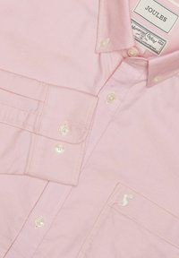 Chemise rose clair à boutons blancs, avec col et logo de lapin blanc brodé sur la poche poitrine, étiquetée Joules.
