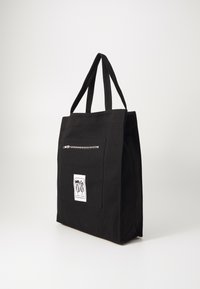 Zwarte tote bag van stof, met twee handvatten, een voorzak met rits en een geborduurd logo op de voorkant.