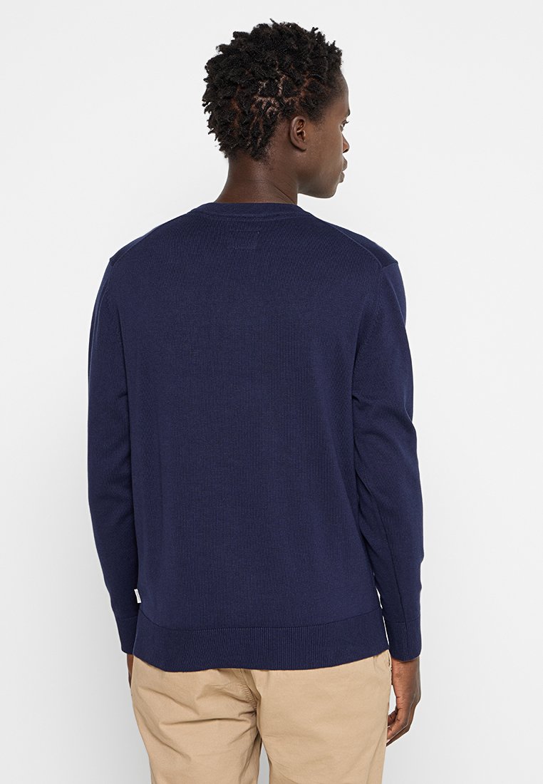 Granatowy sweter z dzianiny z długimi rękawami i prążkowaną teksturą, z gładkim okrągłym dekoltem i prostym wykończeniem.