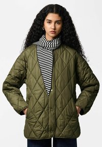 Veste matelassée vert olive avec un design carré, présentant des motifs en losange. Un col roulé rayé noir et blanc est visible au niveau de l'encolure.