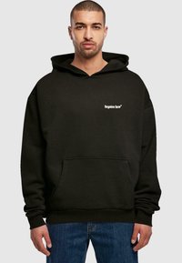 Black hooded sweatshirt made of soft fabric, featuring a front pocket and white text logo on the left chest. Relaxed fit with ribbed cuffs.