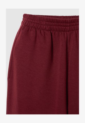 Bordowe dresy z elastycznym pasem i boczną kieszenią, wykonane z miękkiego dzianinowego materiału.