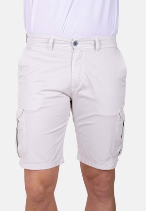 Pantalones cortos cargo beige claros con bolsillos laterales con solapa, llevados por una persona de pie contra un fondo blanco.