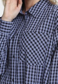 Blue and black checkered button-up shirt made of lightweight fabric, featuring a collar, two chest pockets, and a relaxed fit.