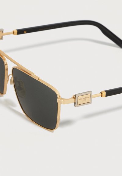Ορθογώνια γυαλιά ηλίου με χρυσό πλαίσιο, μαύρους φακούς, μαύρους βραχίονες και πλακέτα με το λογότυπο Dolce & Gabbana στον βραχίονα.