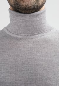 Grå genser med høy hals, i en tettsittende design laget av et fint, teksturert strikket stoff. Har en høy, ribbet krage.