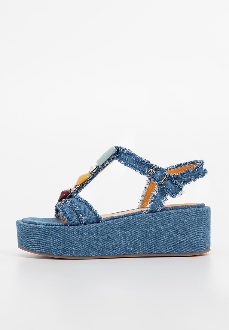 Sandali platform in denim con bordi sfrangiati, molteplici accenti di pietre colorate e una cinghia alla caviglia regolabile per una vestibilità sicura.