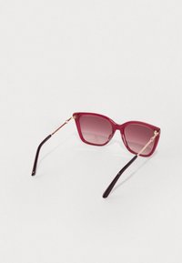 Sončne očala s kvadratnim dizajnom v rdeči gradient barvi, ki vključujejo sijoč okvir, zlat metalni detajli in temno rjavimi ročaji.