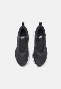 Baskets de sport Noires Nike avec une tige en maille, accents blancs, bout arrondi et semelle plate ; lacets pour un maintien sécurisé ; languette au niveau du talon.