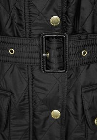 Casaco preto acolchoado com um cinto com fivela quadrada, dois bolsos frontais com botões de pressão dourados e padrões de costura diagonal.