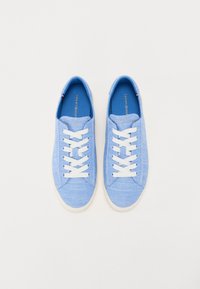 Baskets en toile bleu clair avec des lacets blancs et des semelles en caoutchouc. Présente une texture cousue et une étiquette intérieure de marque.