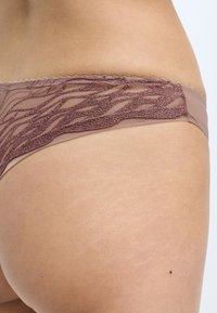 Brown underwear featuring a textured, glittery design along the waistband, with a sheer panel and a smooth fabric finish on the body.