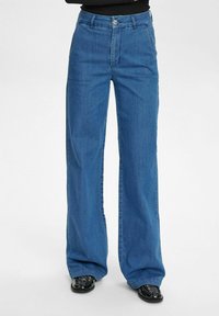 High-waisted, wide-leg blue jeans in denim fabric. Features front pockets, belt loops, and a button closure. Smooth texture and casual fit.