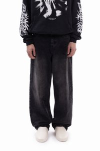 Black graphic hoodie with white designs, featuring a kangaroo pocket. Paired with loose-fitting, faded black denim jeans, and white footwear.