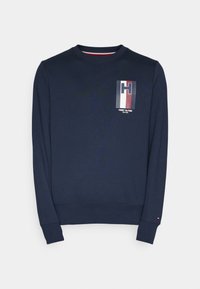 Granatowa bluza z bawełnianej mieszanki, z okrągłym dekoltem, długimi rękawami, z naszywką z logo w kolorach czerwonym, białym i niebieskim na lewej piersi. Ściągacze na mankietach i dole bluzy.