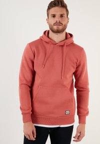 Sudadera color rosa hecha de una suave mezcla de algodón, con un espacioso bolsillo frontal, capucha ajustable y puños y dobladillo acanalados.