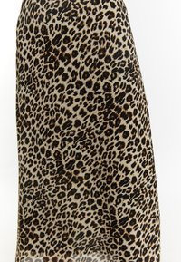 Hame leopard-kuosis, jossa on vaalea beige tausta ja tummanruskeita sekä mustia pilkkuja. Valmistettu sileästä kankaasta, jossa on valuva tekstuuri.
