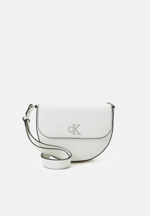 Witte leren crossbodytas met zilveren CK-logo op de klep en verstelbare band met zwarte randen, geplaatst tegen een effen lichte achtergrond.