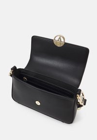 Schwarze Lederhandtasche mit goldenem Hardware, ausgestattet mit einem Frontverschluss, einem Reißverschlussfach und einer glatten Oberfläche. Offen für die Innenansicht.