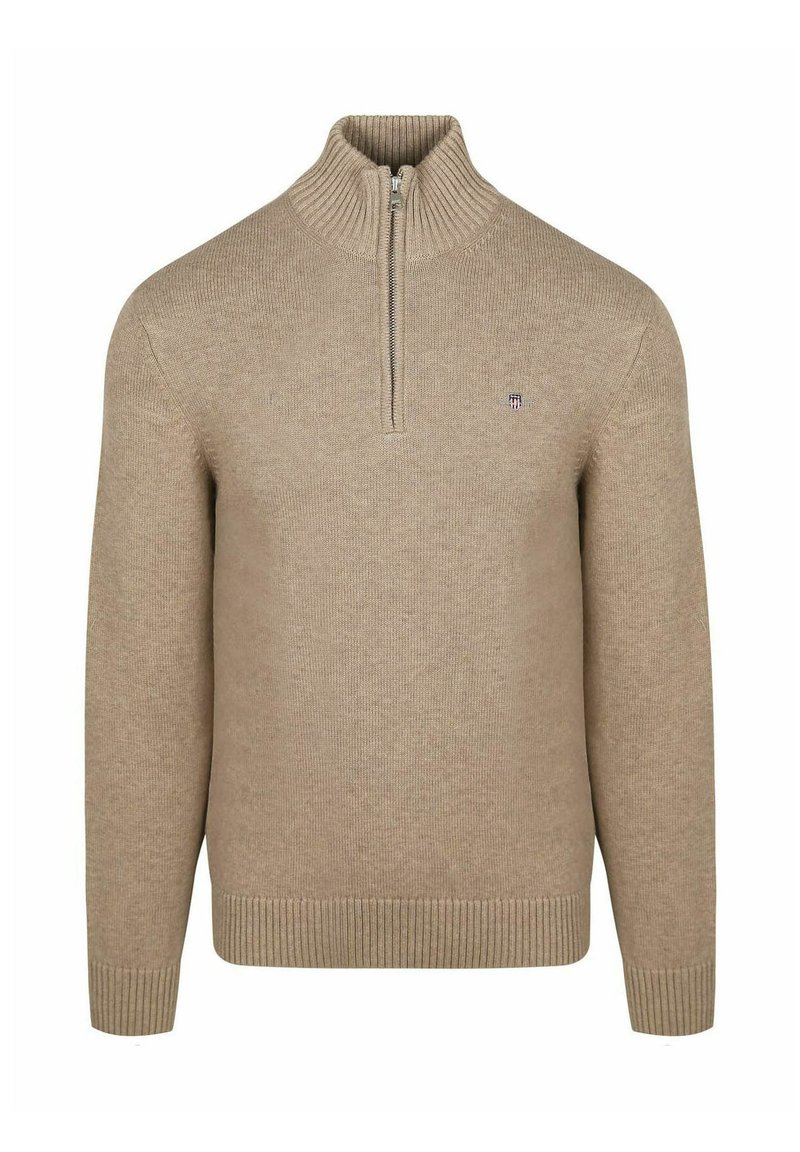 Beige zip-up tröja i ribbad stickad tyg. Har en hög krage samt ribbade ärmslut och nederkant. Liten logga på vänster bröst.