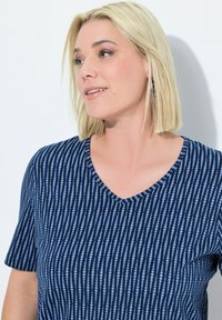 T-shirt a V blu navy con righe verticali blu a pois. Maniche corte e tessuto morbido, presenta una vestibilità comoda e dettagli minimi.
