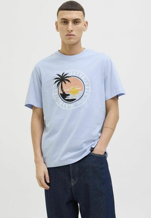 Lys blå kortærmet t-shirt med et cirkulært grafisk design, der viser et palmetræ, solnedgang og teksten "Jack & Jones California". Fremstillet i bomuldsmateriale.