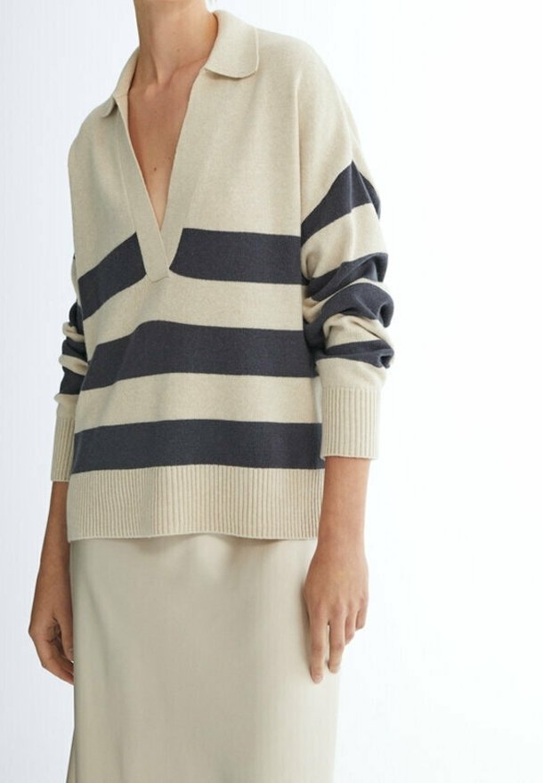 Beige en marineblauwe gestreepte trui met een V-hals en een kraag, voorzien van geribbelde manchetten en een losse pasvorm, gecombineerd met een crèmekleurige rok.