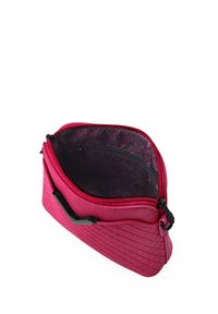 Pink synthetic bag with a geometric exterior pattern. Open zipper reveals a black lining featuring a zigzag design and an interior pocket.