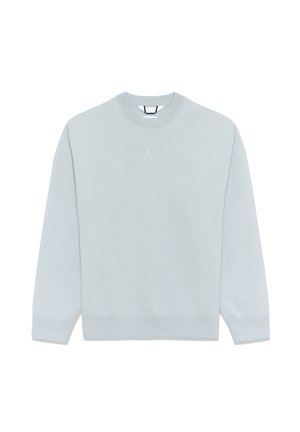 Helehall sinine pusa, tehtud pehmest kangast, ümmarguse kaelusega, pikkade varrukatega ja tikitud risti detailiga esiküljel.