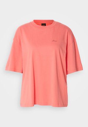 Koraalne üler suured T-särk, mis on valmistatud pehmest puuvillast, omades ümmargust kaelust ja lühikesi varrukasid, koos õrnalt tikitud logoga rinnal.