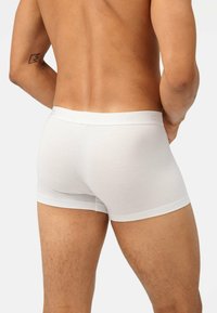 Boxer da uomo bianchi in cotone con un morbido elastico in vita etichettato "OLYMP". Il tessuto appare liscio e aderente, evidenziando i contorni del corpo.