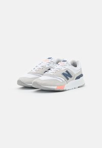 Baskets New Balance en blanc et gris, avec des matériaux en mesh et en daim, un design à lacets, et des accents orange sur la semelle.