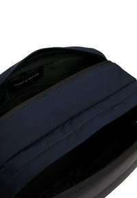 Borsa con cerniera in nylon blu navy con esterno testurizzato, dotata di foderatura nera e etichetta del marchio visibile all'interno. Design semplice e funzionale.