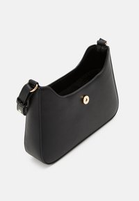 Schwarze Kunstleder-Handtasche mit einzigartiger, geschwungener Form, ausgestattet mit einem goldenen Knopfverschluss und einem verstellbaren Tragegurt. Glatte Textur, minimalistisches Design.
