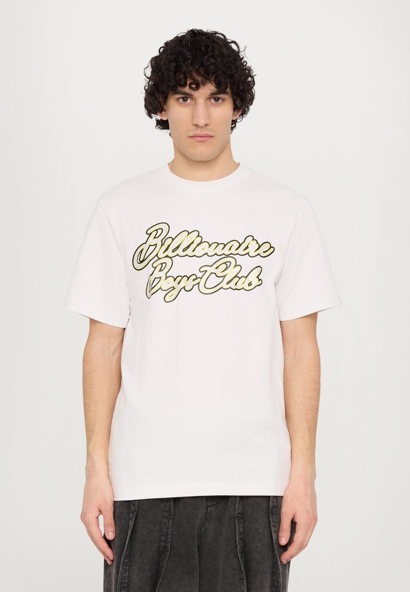 T-shirt en coton blanc avec un logo noir et or "Billionaire Boys Club" en écriture cursive bien en vue. Manches courtes, design à col rond.