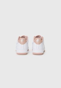Weiße Nike Air Sneaker mit einer weichen rosa Fersenkappe, die mit gesteppten Details und Gummisohlen versehen sind. Die Rückansicht zeigt das Logo und Designelemente.