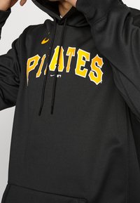 Felpa nera con lettering giallo "PIRATES", logo Nike e cordino. Tessuto morbido e design aderente con tasca frontale.