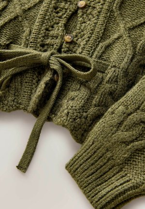Knitted green cardigan with cable design, featuring a tied waist, round buttons, and ribbed cuffs. Textured and chunky knit fabric.