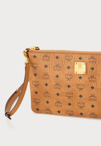 Pochette bracelet en cuir tan avec motif logo MCM, fermeture éclair dorée et petite plaque dorée avec logo et numéro de série.