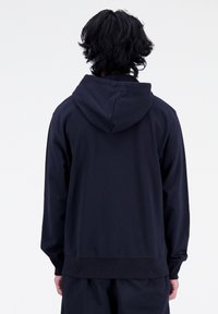 Felpa con cappuccio blu navy caratterizzata da un design semplice, polsini a coste e una finitura testurizzata, vista dal retro.