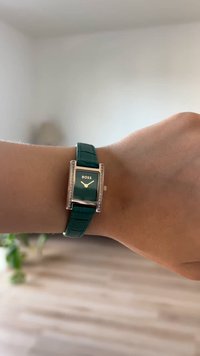 Πράσινο ορθογώνιο ρολόι με χρυσό περίβλημα, κρυστάλλινες λεπτομέρειες και επικαλυμμένο πράσινο δερμάτινο λουρί. Διαθέτει μαύρο καντράν με το λογότυπο 'BOSS'.