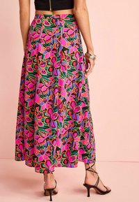 Lange, vloeiende rok met een levendig roze bloemenpatroon op een zwarte achtergrond. Horizontale plooien bij de taille en een uitlopende zoom.