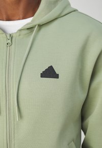 adidas Sportswear FUTURE ICONS THREE STRIPES FULL ZIP - Camisola com fecho - tent green