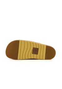 Semelle en caoutchouc avec un design texturé et ondulé en beige, présentant un accent de logo marron et des propriétés non marquantes.