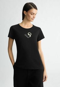 Zwart katoenen t-shirt met een ronde hals en korte mouwen, versierd met een gestileerd, lichtgekleurde grafisch ontwerp op de voorkant.