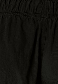 Černá tkanina s hladkou texturou, se skládacím elastickým pasem a jemnými švy podél švů.