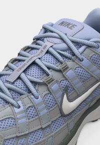 Ανοιχτό μπλε αθλητικό παπούτσι Nike με υφασμάτινο δίχτυ, γκρι επενδύσεις, λευκό λογότυπο swoosh και σύστημα γρήγορου δέσίματος με την ετικέτα "Bowerman Series".