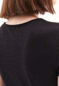 T-shirt nera a maniche corte con scollatura rotonda e texture morbida, vista dal retro con dettagli di cucitura minimi.