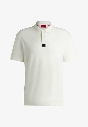Vit polo t-shirt med en strukturerad krage, framknäppning med knappar, och en svart märkesetikett på bröstet. Slät, lättviktsmaterial.