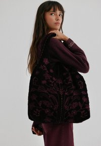 Fluwelen draagtas in diep paars met bloemenborduurwerk, met een grote afgeronde vorm, ingewikkelde stiksels en kraalversieringen.